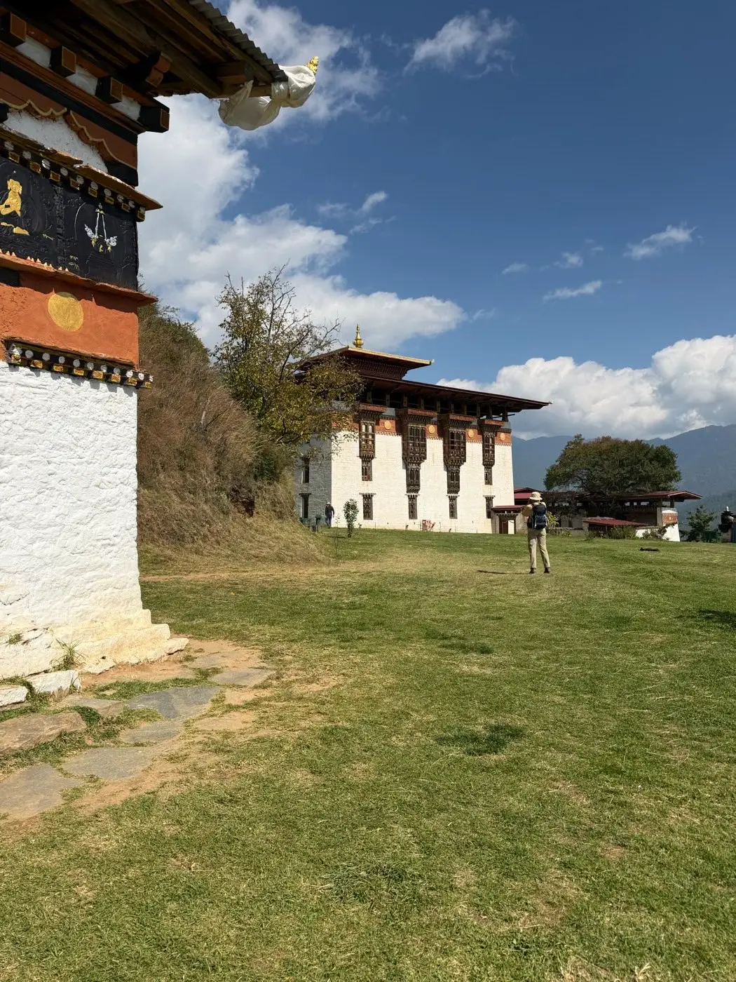 Whitewashed dzong set on a green lawn under a blue sky